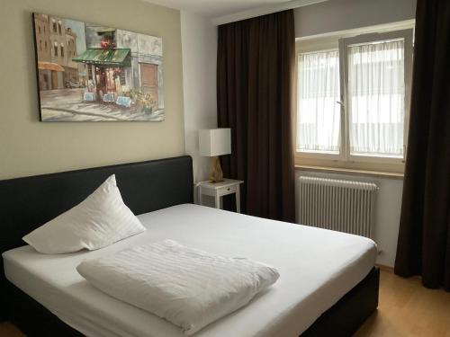 Schlafzimmer mit einem weißen Bett und einem Fenster in der Unterkunft Hotel Berg in Seekirchen am Wallersee