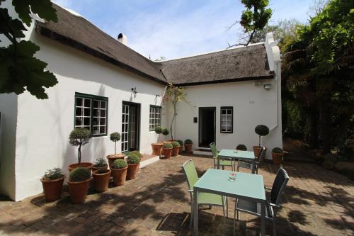 a white house with tables and chairs and potted plants at Rothman Manor in Swellendam