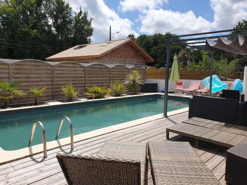 einen Pool mit Stühlen und eine Holzterrasse in der Unterkunft Villa indépendante avec piscine in Arès