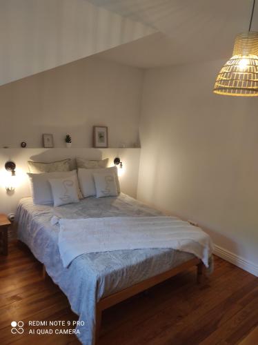1 dormitorio con 1 cama con sábanas y almohadas blancas en Les Hôtes Pyrénées, en Capvern