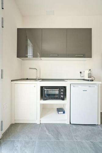 a white kitchen with a sink and a microwave at monolocale incantevole in Visnadello