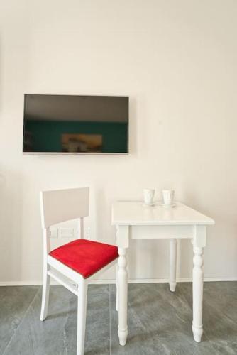 a white table with a red chair and a white table at monolocale incantevole in Visnadello