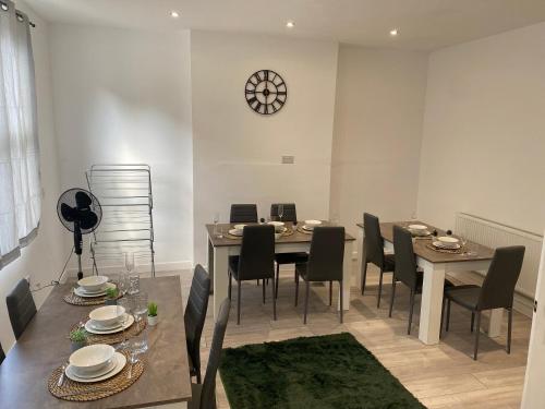 a dining room with a table and chairs and a clock at Stylish Home - Close to City Centre, Anfield Stadium - Free Parking in Litherland