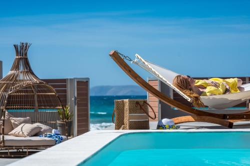 a woman sitting in a hammock next to a swimming pool at Anasa Luxury Villas in Kokkíni Khánion