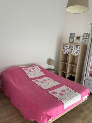 um quarto com uma cama com um cobertor rosa em agréableT2 em Soustons