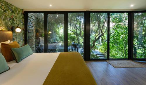 a bedroom with a large bed and large windows at Casa Vela Boutique House in Cascais