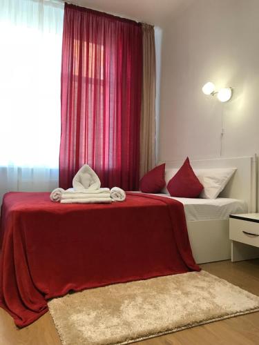 a bedroom with a bed with red sheets and a window at Light Apartments in Chernihiv