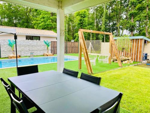 - une table et des chaises dans un jardin avec piscine dans l'établissement Maison 3 chambres avec piscine chauffée, à Mios