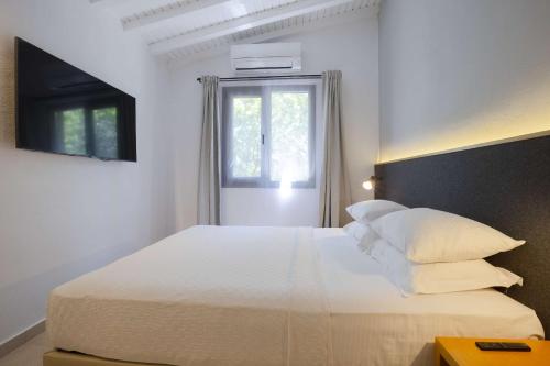 a white bedroom with a large bed and a window at AEGEAN Apartments - Bungalows in Alaçatı
