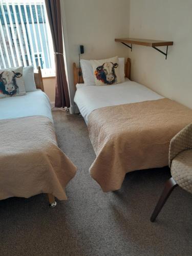 a room with two beds and a chair and a window at Parkhill Guest House in Inverness