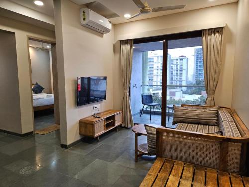 a living room with a television and a large window at Hotel Tattva Suites in Pune