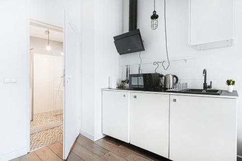 a kitchen with white cabinets and a tv on the wall at Komfortowy apartament w samym centrum Wrocławia in Wrocław