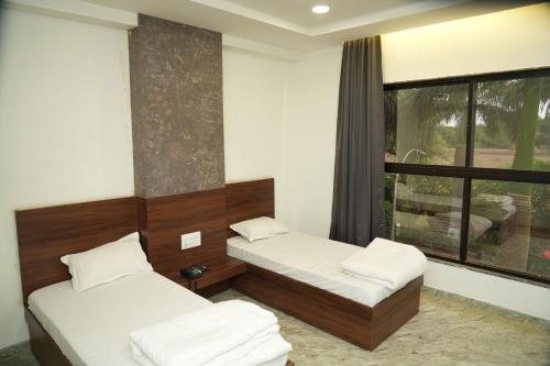 2 Betten in einem Zimmer mit Fenster in der Unterkunft Madhuban Garden And Resort 