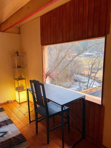 a table and a chair in a room with a window at Fain in Lunca Bradului