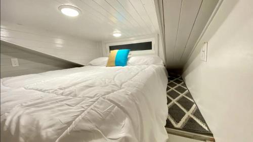 a bedroom with a white bed with a yellow and blue pillow at Bolivar Tiny Home #3 in Bolivar Peninsula