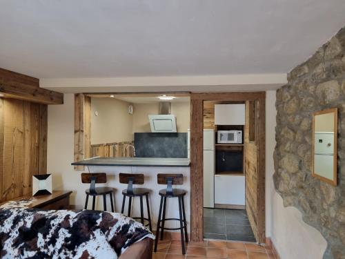 a room with a kitchen and a bar with stools at Orri de Planès in Planès