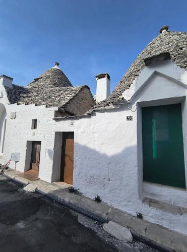 a white building with a green door on a street at Tipico Resort in Alberobello