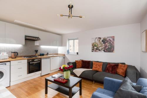 a living room with a couch and a kitchen at Stunning Flat 5 min from Station in London