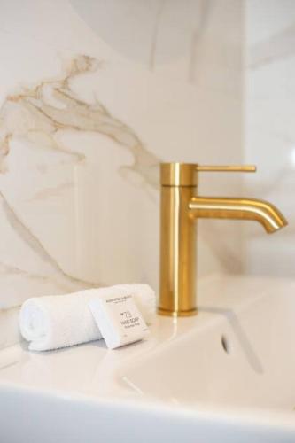 een wastafel in de badkamer met een gouden kraan en een handdoek bij Anegang Boutique Hotel in Haarlem
