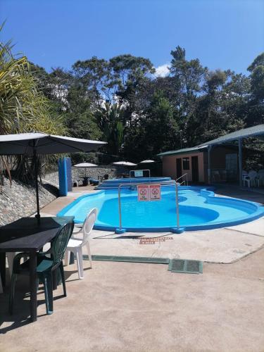 a large swimming pool with chairs and an umbrella at Centro Ecológico La Ribera-CABAÑA 3 in San Rafael