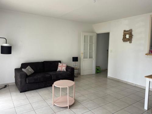 sala de estar con sofá negro y taburete rosa en Rochel, en Marmande