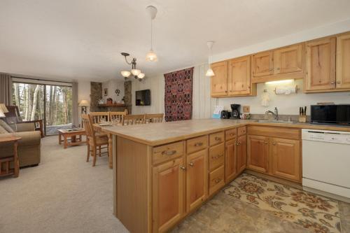 a kitchen with wooden cabinets and a living room at Beaver Village Unit #0712R in Winter Park