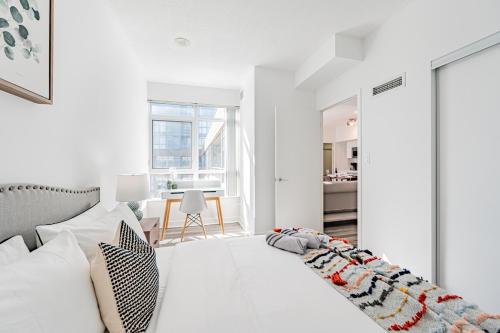 Habitación blanca con cama blanca y mesa en Dan Leckie Apartments, en Toronto