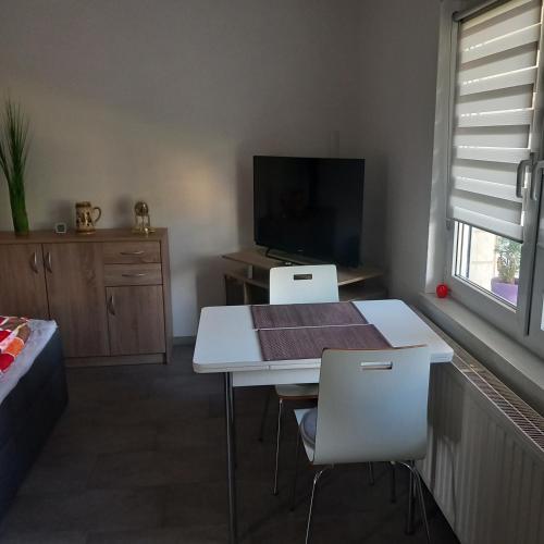 a living room with a white table and chairs and a tv at Gästezimmer Melz in Rüdersdorf