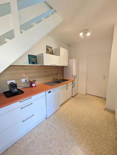 - une cuisine avec des placards blancs, un évier et un escalier dans l'établissement Maison de vacances - 4 chambres - Portiragnes-Plage, à Portiragnes