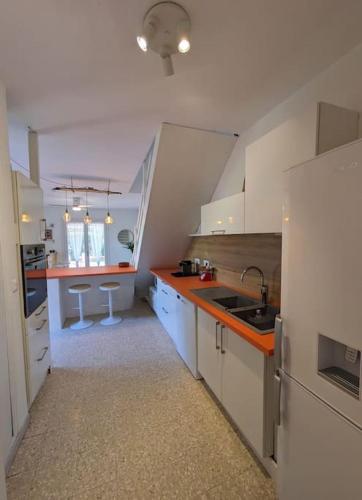 une cuisine avec des armoires blanches et des comptoirs orange dans l'établissement Maison de vacances - 4 chambres - Portiragnes-Plage, à Portiragnes
