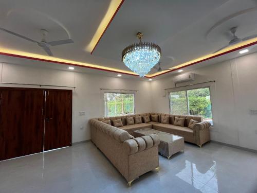 a living room with a couch and a chandelier at Reet Farms in Noida