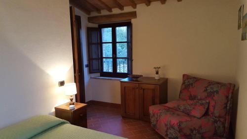 a bedroom with a bed and a chair and a window at Podere Piemonti in Serre di Rapolano