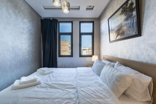 a bedroom with a large white bed with two windows at Stylish Studio à Ain Sebaa in Casablanca