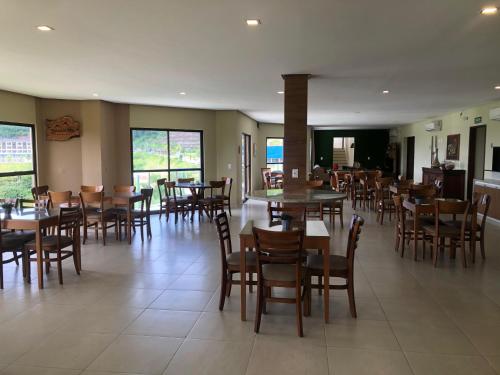 a dining room with tables and chairs and windows at Pousada Da Serra in Bananeiras