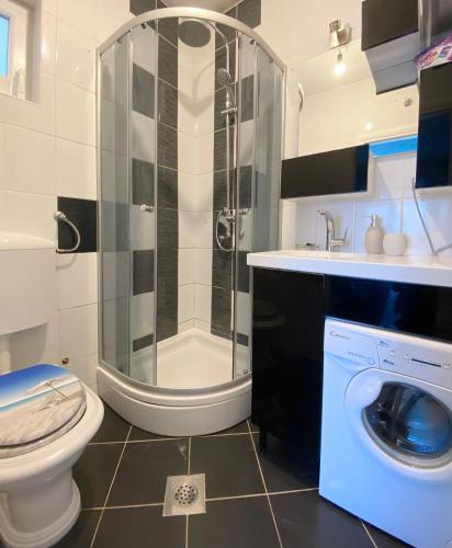a bathroom with a shower toilet and a washing machine at Apartment Andrija in Baška Voda