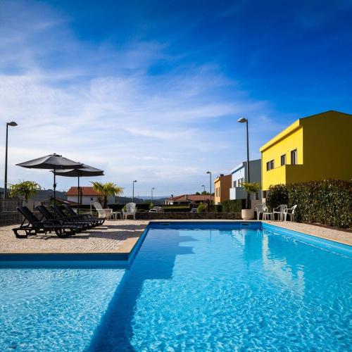 una piscina con sillas y sombrillas junto a un edificio en Outeiro Villas Resort, en Barcelos