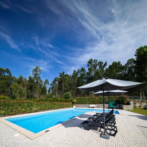 una sombrilla y sillas junto a la piscina en Outeiro Villas Resort, en Barcelos