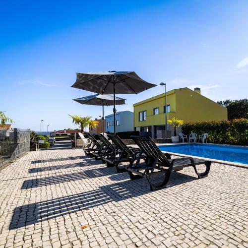 a row of chairs with umbrellas next to a pool at Outeiro Villas Resort in Barcelos