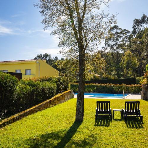 two chairs sitting next to a tree in a yard at Outeiro Villas Resort in Barcelos