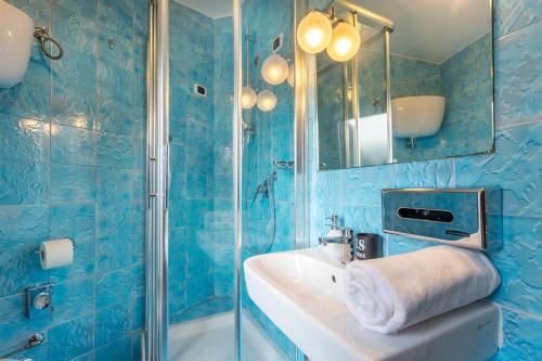 bagno piastrellato blu con lavandino e specchio di Maxi Paradiso a Torricella