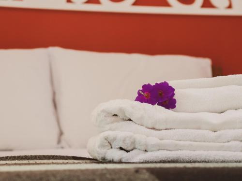 uma pilha de toalhas e uma flor roxa numa cama em Hospedagem Donalu - Vale do Capão em Palmeiras
