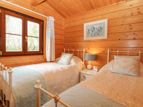 1 dormitorio con 2 camas en una cabaña de madera en Kingfisher Lodge 