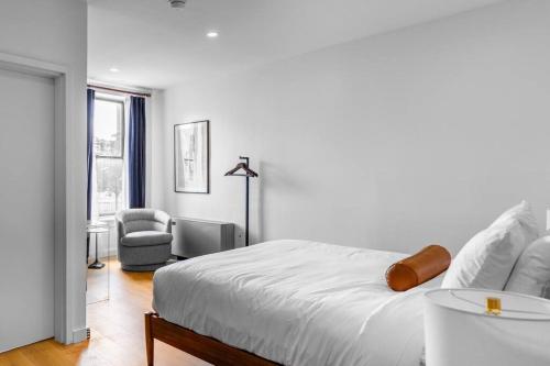 a white bedroom with a bed and a chair at DTWN Bangor, Historic Hotel, Coffee Shop in building, Room # 105 in Bangor