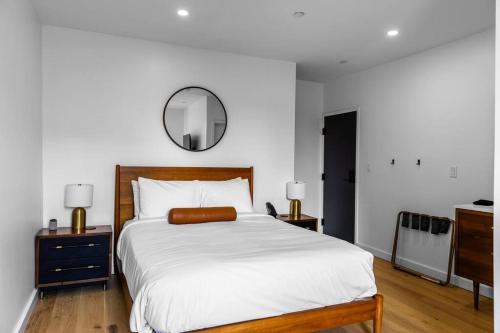 una camera da letto con un grande letto bianco e uno specchio di DTWN Bangor, Historic Hotel, Coffee Shop in building, Room # 105 a Bangor