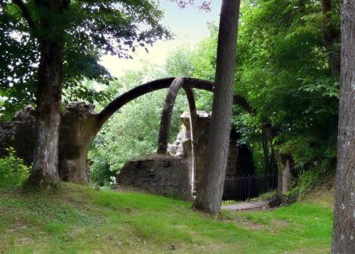 un arco de piedra en un parque con árboles y césped en Chambre d'hote les frérots, en Lurcy-le-Bourg