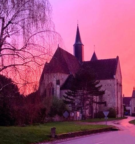eine alte Kirche mit rosa Himmel im Hintergrund in der Unterkunft Chambre d'hote les frérots in Lurcy-le-Bourg