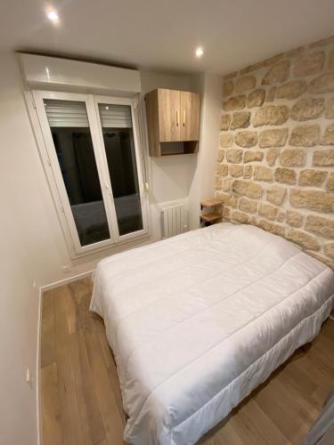 une chambre avec un grand lit avec un mur en pierre dans l'établissement Appartement neuf à louer, Paris Sacré Cœur, à Paris