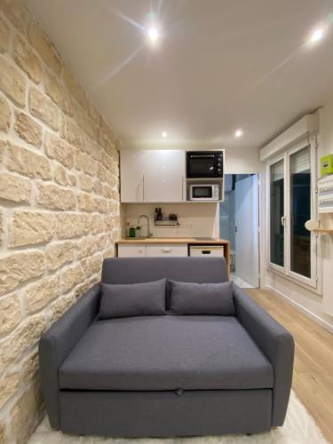 - un canapé dans le salon avec un mur en pierre dans l'établissement Appartement neuf à louer, Paris Sacré Cœur, à Paris