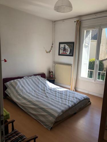 une chambre avec un lit dans une pièce avec une fenêtre dans l'établissement L'aubaine, à Saint-Aubin-sur-Mer