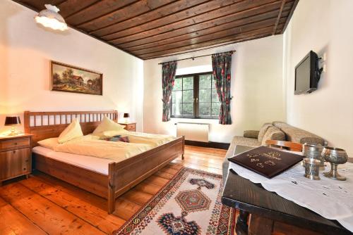 a bedroom with a bed and a table and a tv at Pension Pilsachhof in Arriach